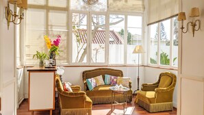 Una habitación iluminada por el sol con un sofá, dos sillones, una mesita y un florero.