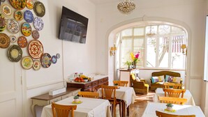 Un comedor con sillas y mesas de madera, un televisor montado en la pared y una variedad de platos decorativos en la pared.