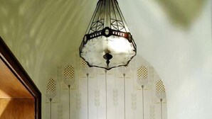 A room with a patterned sofa, a hanging light fixture, and vertical decorative elements on the wall.