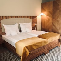 Una habitación de hotel con cama, mesita de noche, lámpara de pared y piso con diseño.