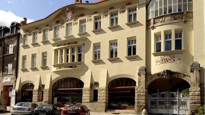 A historic building with multiple windows, a stone facade, and a sign indicating it is a hotel.