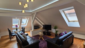 Ein modernes Loft-Apartment mit Essbereich, Sitzgelegenheiten, einem Fernseher und Dachfenstern.