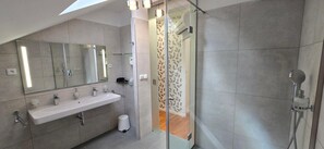 Un baño moderno con tragaluz, un espejo grande, ducha y retrete.