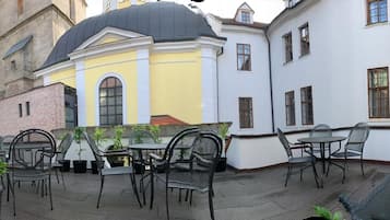 An outdoor seating area with metal chairs and tables, surrounded by buildings with distinct architectural styles.