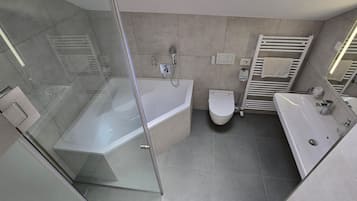 A modern bathroom with a glass-enclosed shower, a standalone bathtub, a toilet, and a vanity with a sink.