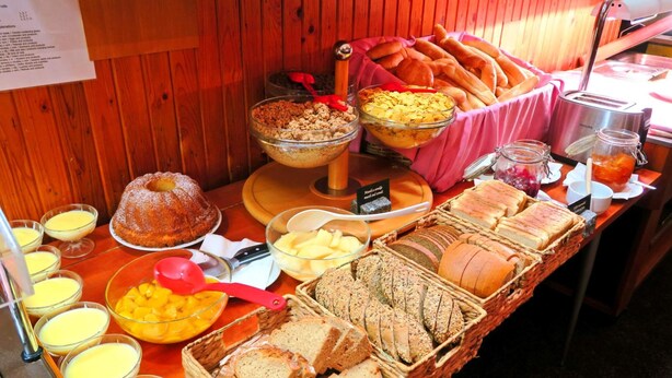 A buffet with various food items including bread, pastries, and a cake. - Hotel Harrachov Inn (Harrachov)