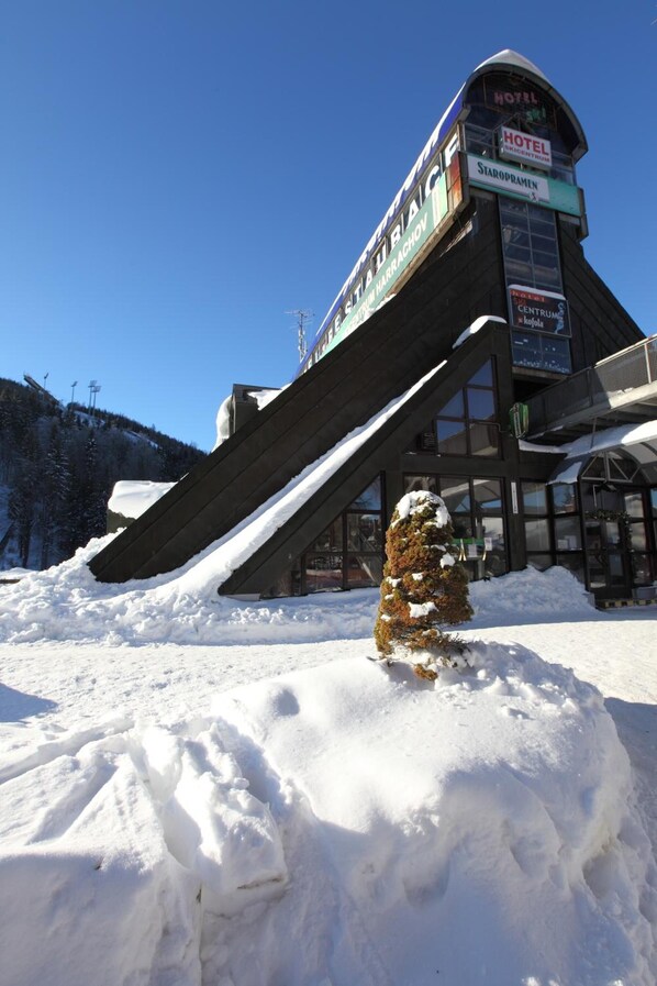 A hotel with a ski lift, snow-covered surroundings, and a clear blue sky. - Hotel Skicentrum (Harrachov)