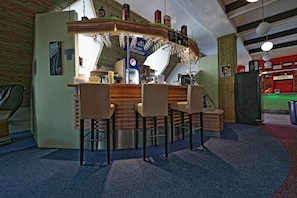 Zona de bar con tres taburetes, una barra con refrigerador de Pepsi y un mostrador de recepción.