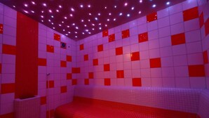 A room with a tiled floor and walls, a bench, and a ceiling with lights. - Hotel Skicentrum (Harrachov)