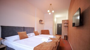 A hotel room with a large bed, two bedside tables, a flat-screen TV mounted on the wall, and a small shelf with a plant. - Hotel Skicentrum (Harrachov)