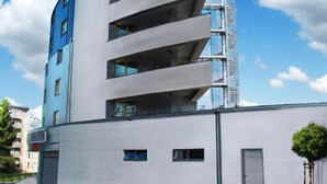 A modern multi-story building with a curved facade, large windows, and a visible staircase on the right side. - Hotel Arena (Liberec)