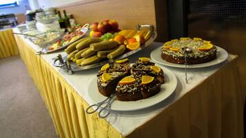 A buffet table with various food items including fruits, vegetables, and a cake.