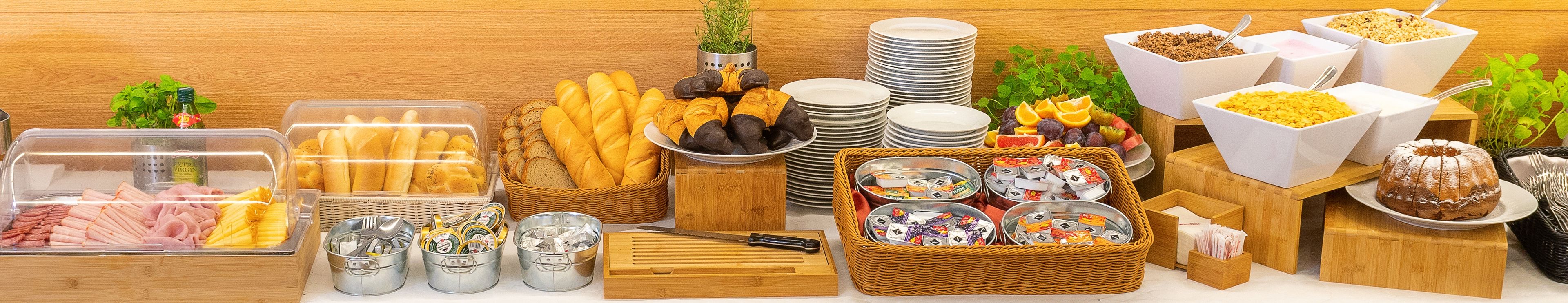 Una barra de buffet con diversos alimentos, entre ellos carnes, panes y frutas.