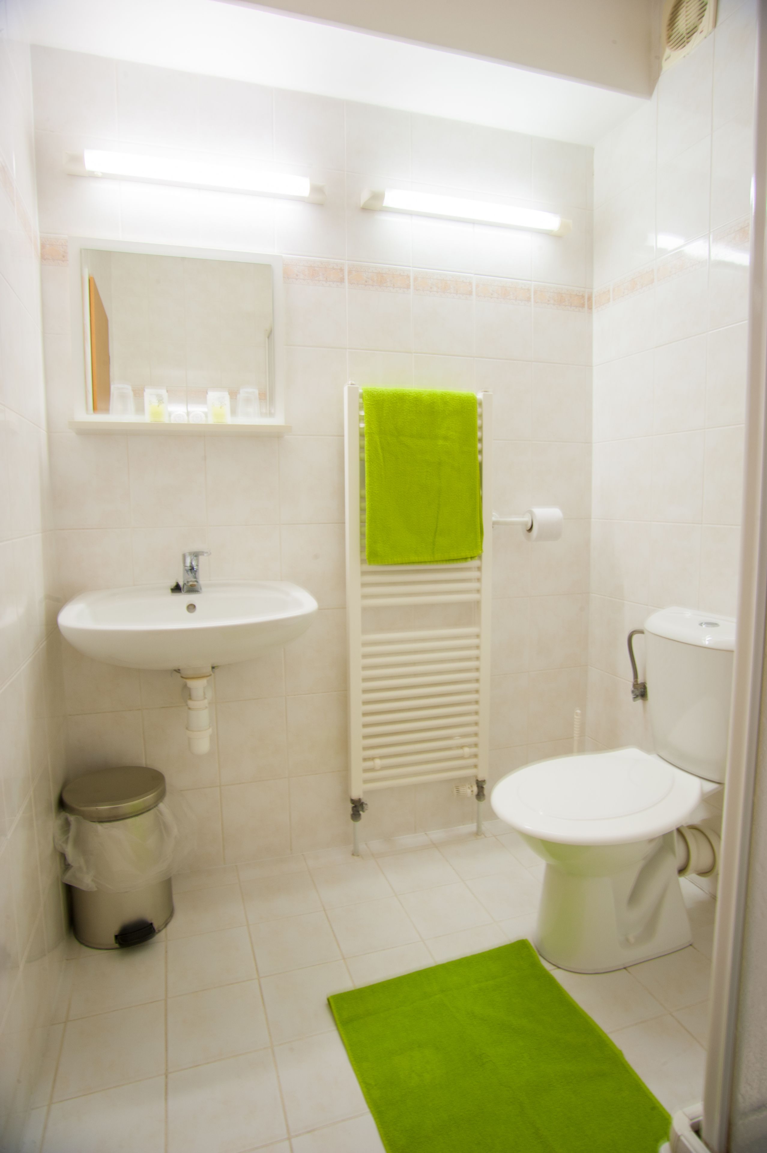 A bathroom with a sink, toilet, and a green towel on the radiator.