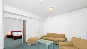 A room with a bed, two sofas, a glass coffee table, and a nightstand. - Hotel Arena (Liberec)