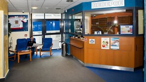 A reception area with a wooden counter, blue chairs, and a sign that reads "RECEPCHE". - Hotel Arena (Liberec)