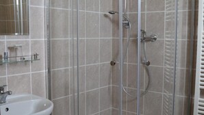 A glass-enclosed shower stall with a white sink and mirror. - Hotel Petra (Liberec)