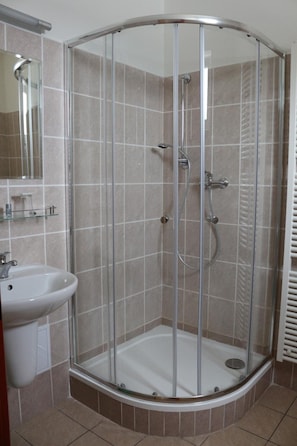 A glass-enclosed shower stall with a white sink and mirror. - Hotel Petra (Liberec)