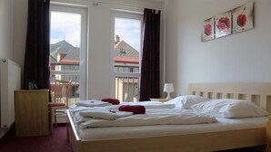 A hotel room with a bed, a chair, a desk, and a window with curtains. - Hotel Petra (Liberec)