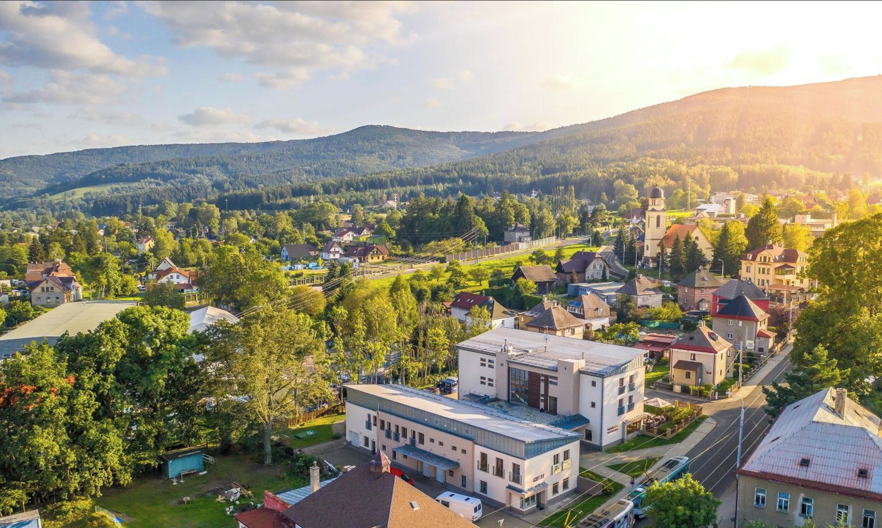 Eine Stadt mit einer Mischung aus Wohn- und Geschäftsgebäuden, einer markanten Kirche und einer hügeligen Landschaft im Hintergrund.