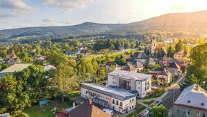 A town with a mix of residential and commercial buildings, a prominent church, and a hilly backdrop. - Hotel Petra (Liberec)