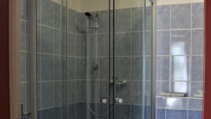 A shower enclosure with a glass door, a toilet, and a tiled wall. - Hotel Petra (Liberec)