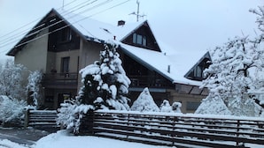 A snow-covered building with a balcony and a staircase leading to the entrance.