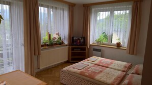 A cozy room with a bed, a TV, and a window with curtains.