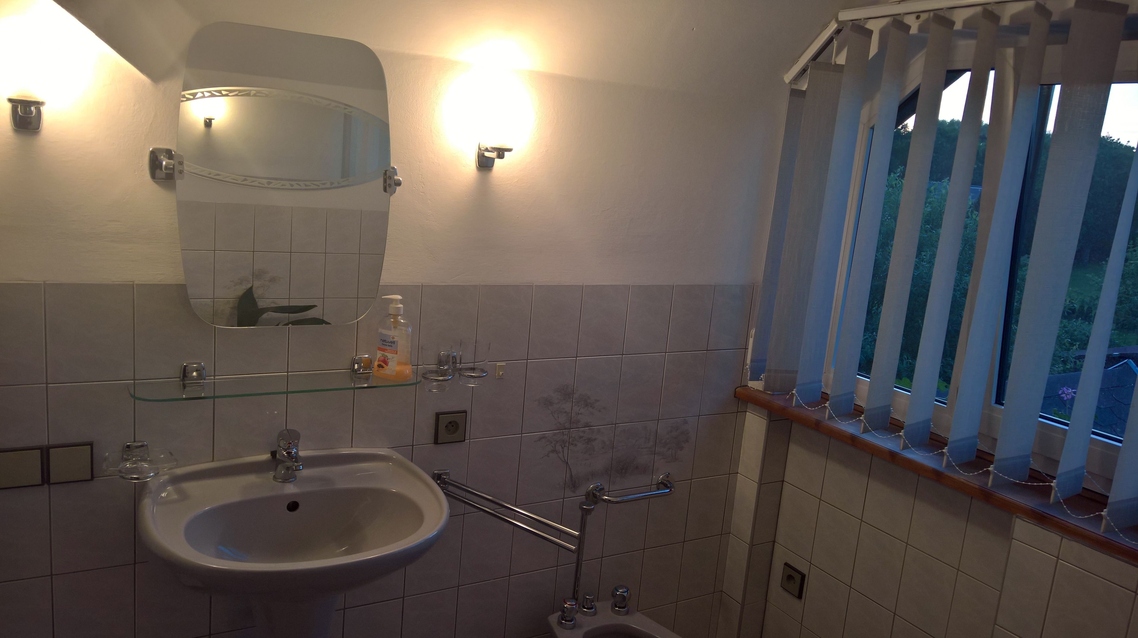 A bathroom with a sink, mirror, and shower.