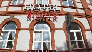 Un hotel con un cartel llamativo, ventanas en arco y fachada de piedra.