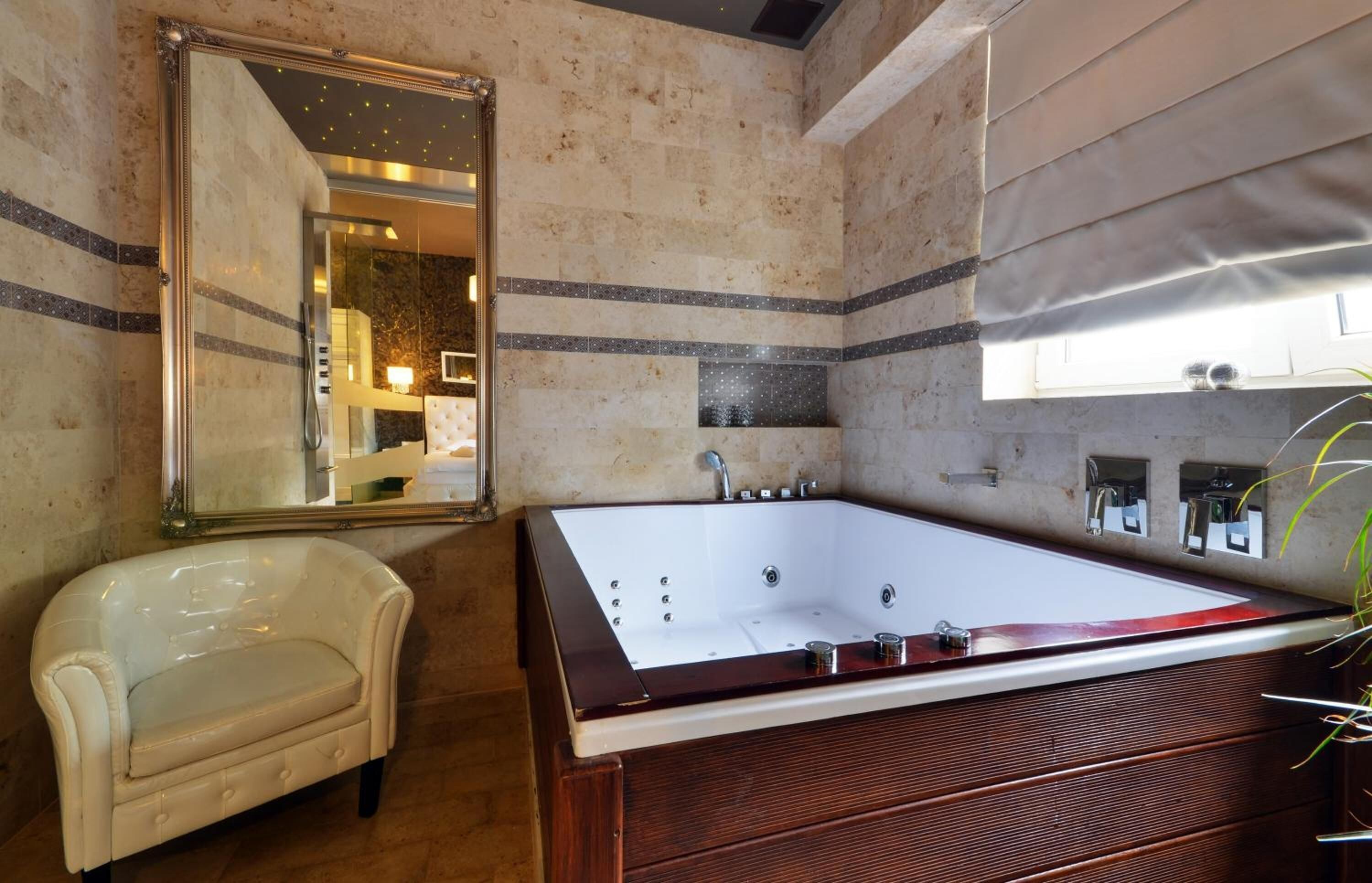 Un baño con una bañera grande, un espejo, un tocador y una silla.