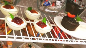 Mostrador refrigerado con diversos alimentos, incluyendo postres y aperitivos.