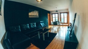 Ein modernes Wohnzimmer mit einem schwarzen Sofa, einem Couchtisch und einem Essbereich mit Tisch und Stühlen.