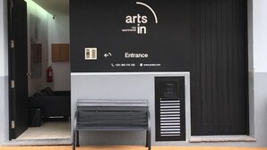 Ein Gebäudeeingang mit einem Schild, auf dem 'arts in city apartments' steht, und einem darunterliegenden Schild mit der Aufschrift 'Eingang'.