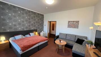 Una habitación de hotel con una cama, un sofá, una mesita, un televisor y un cuadro en la pared.