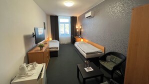 Habitación de hotel con cama, escritorio, computadora, silla, mesita y televisor.