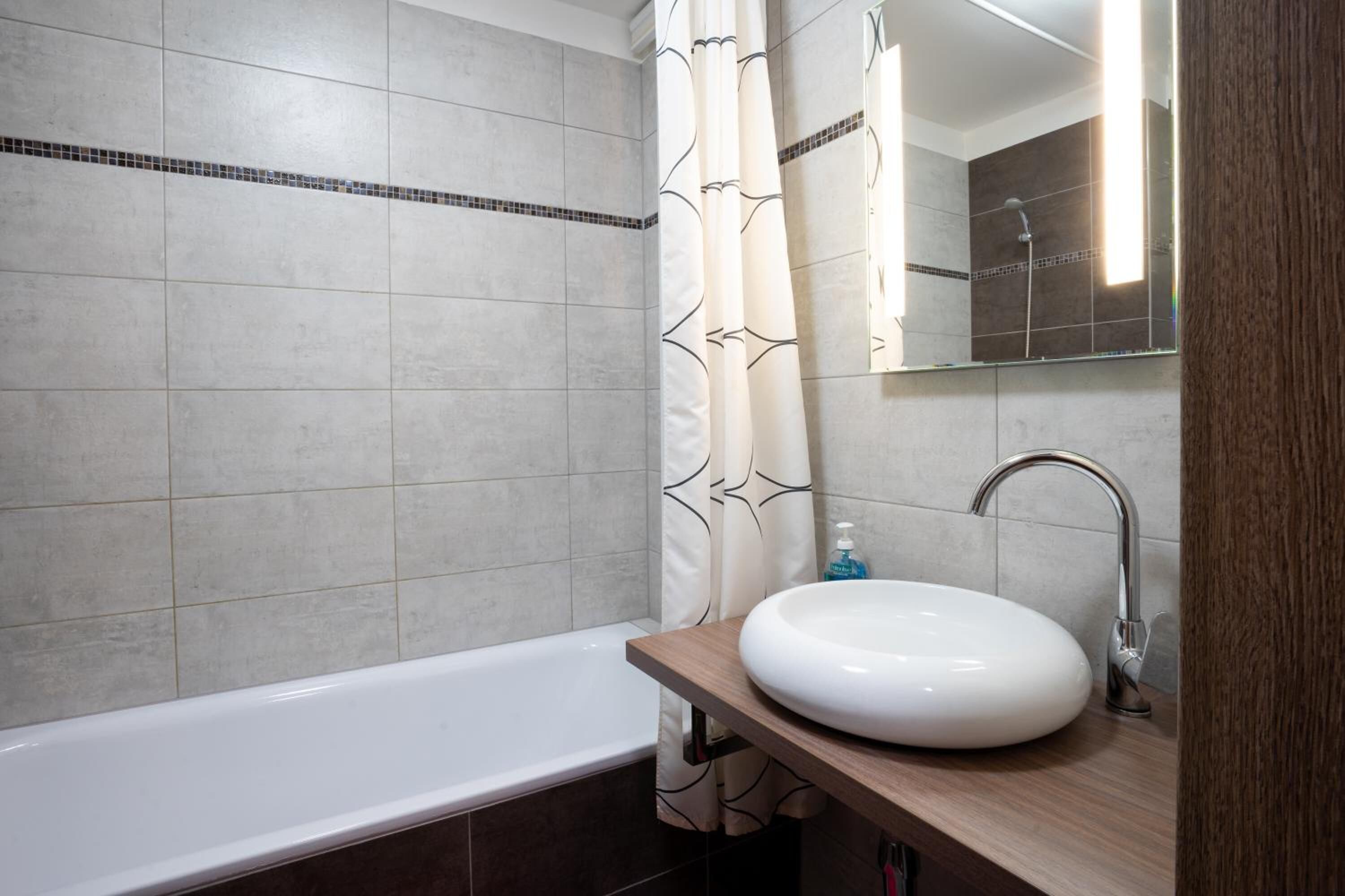 A modern bathroom with a bathtub, a round sink, and a shower.