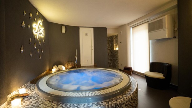Un cuarto de spa con un jacuzzi, una luz de spa instalada en la pared y una puerta.