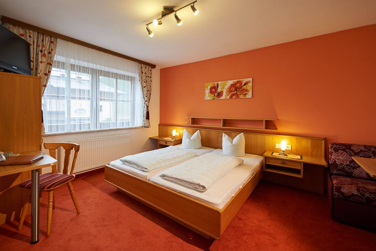 Une chambre d’hôtel avec un grand lit, un bureau, une chaise et une fenêtre avec des rideaux.