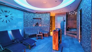 Un área de spa moderna con un reloj, asientos, una recepción y una sala de masajes.