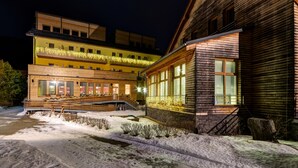 Un edificio de varios pisos con fachada de madera, ventanas amplias y suelo cubierto de nieve.