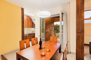 A dining area with a wooden table, two wine glasses, and a bottle of wine.