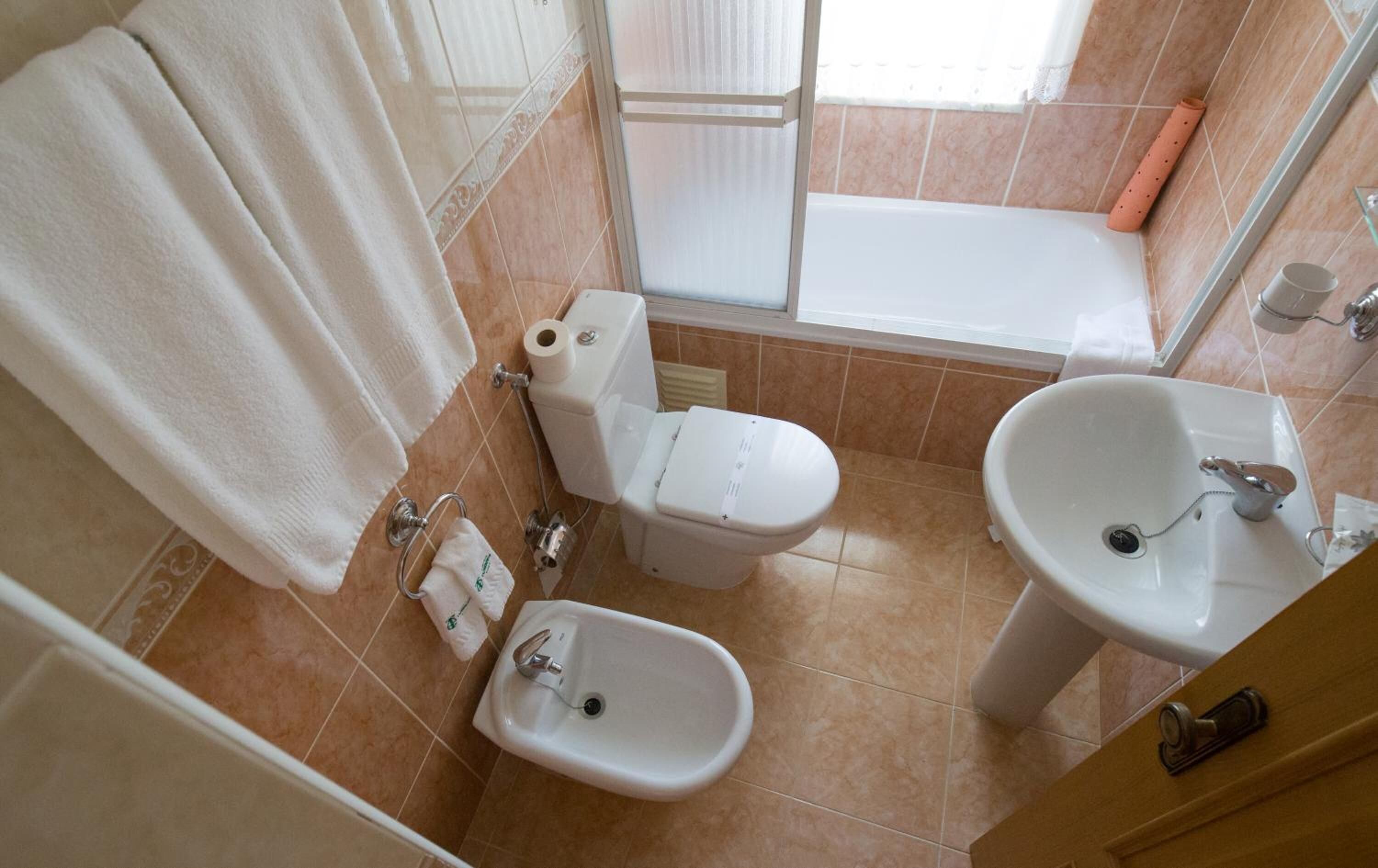 A bathroom with a toilet, bidet, sink, and bathtub.