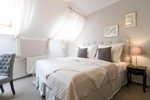 Une chambre à coucher avec un lit, une chaise, une table de chevet avec une lampe et une fenêtre avec des rideaux.