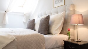 A neatly made bed with a quilted cover, a bedside lamp, a vase with a flower, and a framed picture on the wall. - U Solné Brány (Ceské Budejovice (Budweis))