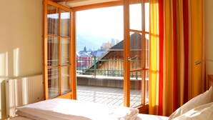 A bedroom with a large window, a bed, and a view of a balcony with a railing. - Hotel Binggl (Mauterndorf)