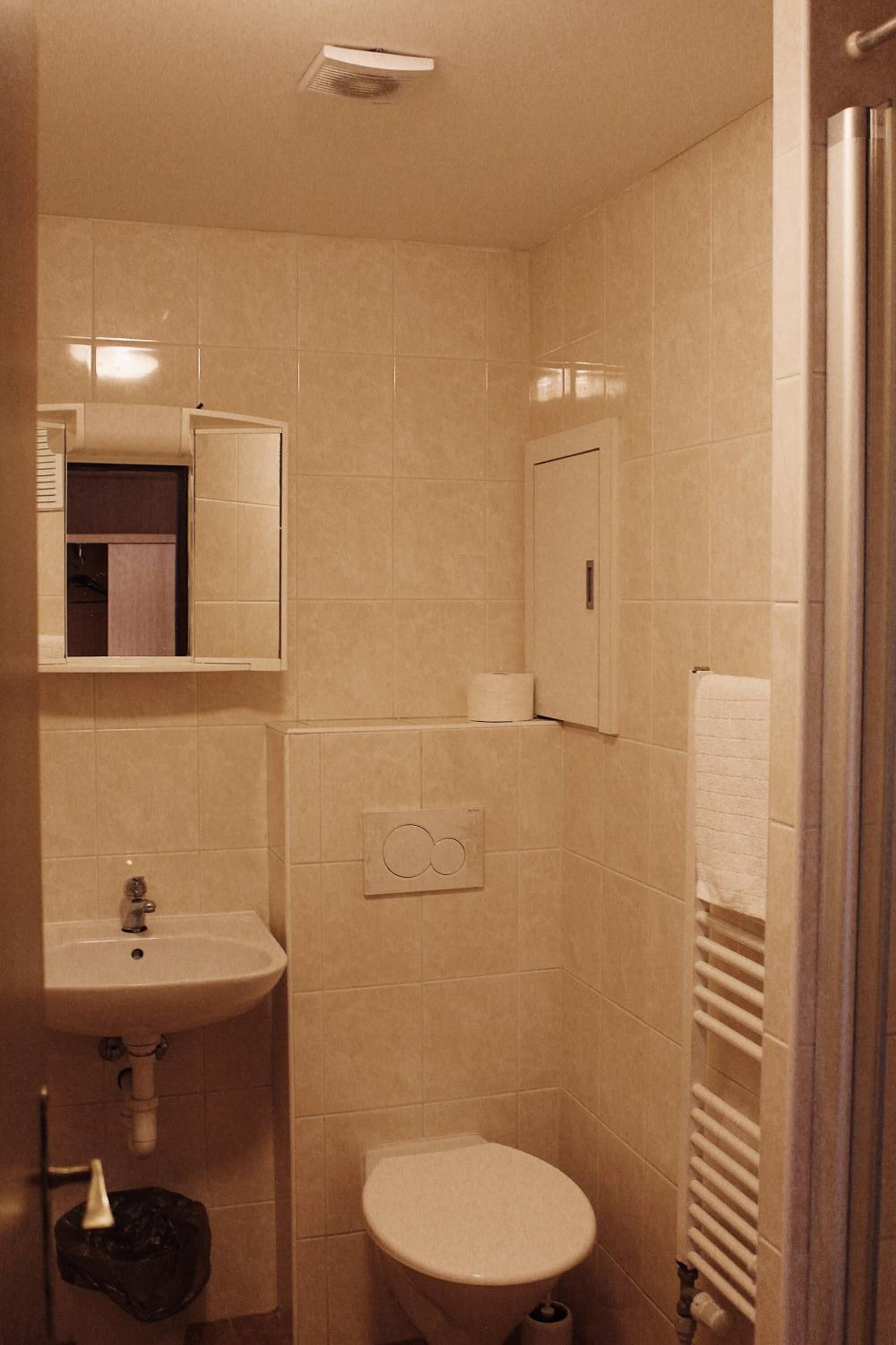 A small, compact bathroom with a sink, toilet, and a mirror.