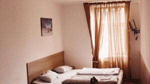A small, single-bed room with a wooden headboard, a bedside table, and a chair. - Amphone (Brno)