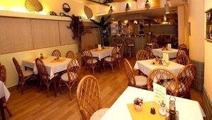 A restaurant with wooden floors, wicker chairs, and white tablecloths. - Amphone (Brno)