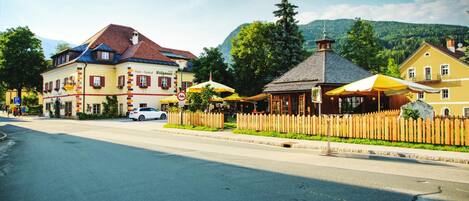 A street view with a hotel, a café, and a mountain backdrop.
